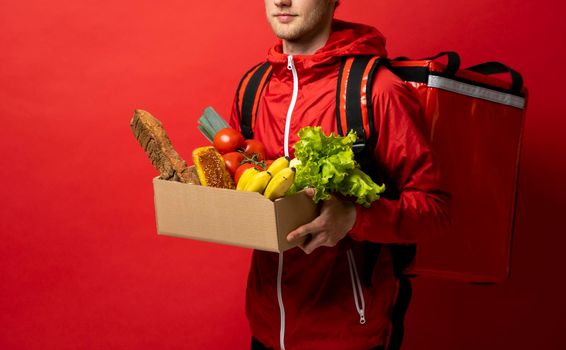 Delivery Concept - Handsome delivery man carrying package box of grocery food and drink from store