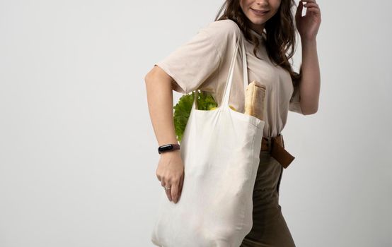 Woman holding textile grocery bag with vegetables. Zero waste concept. Package-free food shopping. Eco friendly natural bag with organic fruits and vegetables