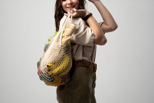 Girl is holding mesh shopping bag with vegetables, greens without plastic bags. Zero waste, plastic free. Eco friendly concept. Sustainable lifestyle