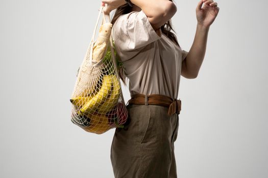 Zero waste concept. Young woman holding reusable cotton shopping mesh bag with groceries from a market. Concept of no plastic. Zero waste, plastic free. Eco friendly concept. Sustainable lifestyle