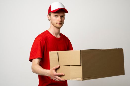 Deliveryman in a red unifor and a cap carrying a parcel box