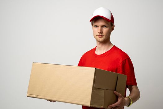 Delivery man holding cardboard box delivering postal package over white studio background