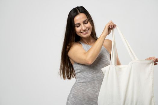 Ecology Concept. Woman holding cotton grocery bag with vegetables. Reusable eco bag for shopping. Zero waste concept. Eco friendly lifestyle. Isolated white background