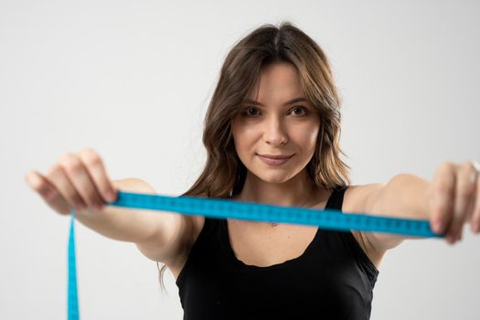 Closeup photo of a Caucasian woman's leg. She is measuring her thigh with a yellow metric tape measure after a diet