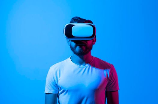 Bearded man using VR headset helmet to interacts with metaverse using swipe and stretching gestures. Watching virtual reality 3d video. Man in VR goggles looking around