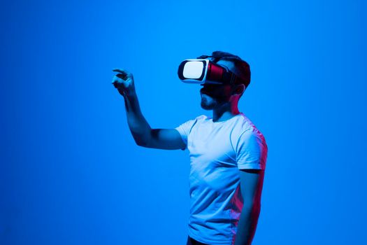 Portrait of man in black t-shirt wearing 3d headset glasses gesturing as if touching something what he doing in virtual reality while playing video games. Metaverse