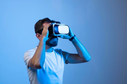 Attractive young man in black t-shirt wearing virtual reality headset or 3d glasses. Handsome male using VR headset and playing video games