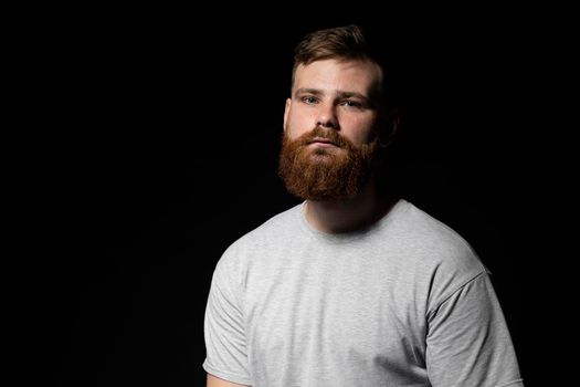 Close-up portrait of a handsome a brunette brutal bearded man in a grey t-shirt. Stylish and handsome man with a beard