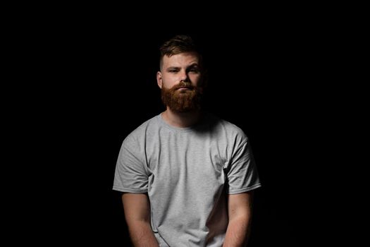 Close-up portrait of a handsome a brunette brutal bearded man in a grey t-shirt. Stylish and handsome man with a beard