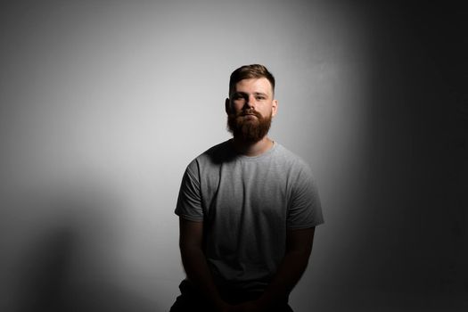 Close-up portrait of a handsome a brunette brutal bearded man in a grey t-shirt. Stylish and handsome man with a beard