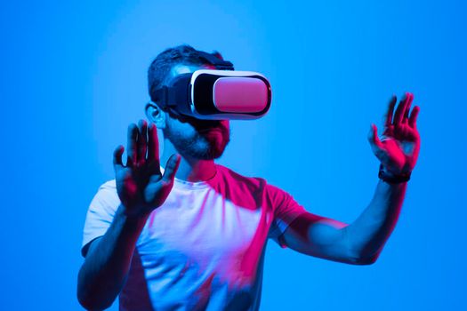 Vitrual reality concept. Man are playing a game in virtual reality. Young man in VR glasses are gaming with realistic holograms in simulator. Entertainment and leisure concept. Modern technologies