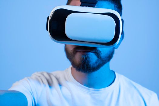 Young man using VR headset helmet to play simulation game. Watching virtual reality 3d video. Bearded man in VR goggles looking around