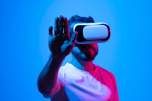 Amazed young bearded man, wearing high tech smart vr goggles, watching 360 degree video or playing a video game in metaverse