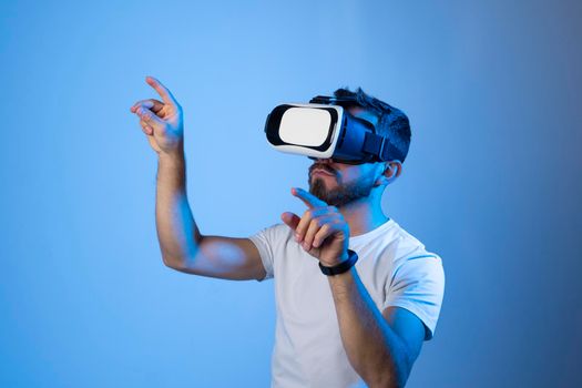 Man in virtual 3d glasses, working on imaginary display in a studio. Man playing video games at home using vr goggles