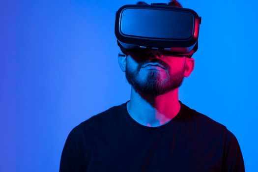 Bearded man using VR headset helmet to interacts with metaverse using swipe and stretching gestures. Watching virtual reality 3d video. Man in VR goggles looking around