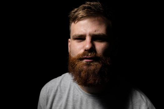 Close-up portrait of a handsome a brunette brutal bearded man in a grey t-shirt. Stylish and handsome man with a beard