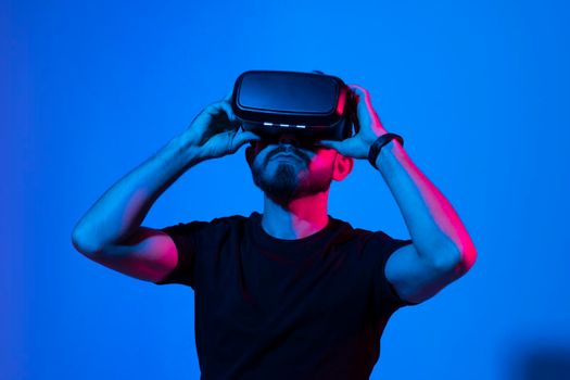 Bearded man in virtual reality headset communicate with a friends in a metaverse. Young man playing a vr video game