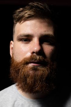 Close-up portrait of a handsome a brunette brutal bearded man in a grey t-shirt. Stylish and handsome man with a beard