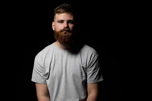 Close-up portrait of a handsome a brunette brutal bearded man in a grey t-shirt. Stylish and handsome man with a beard