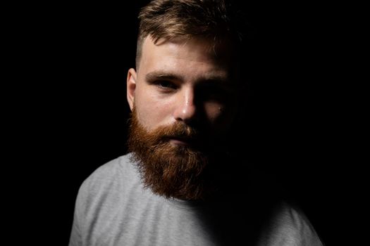 Close-up portrait of a handsome a brunette brutal bearded man in a grey t-shirt. Stylish and handsome man with a beard