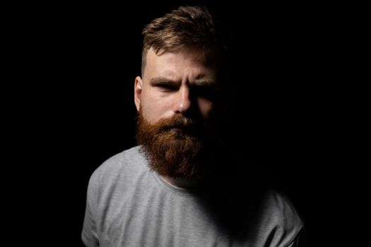 Close-up portrait of a handsome a brunette brutal bearded man in a grey t-shirt. Stylish and handsome man with a beard