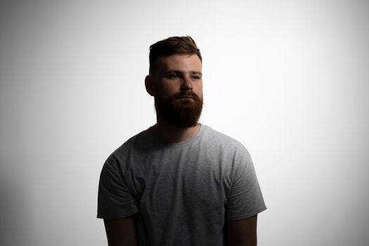 Close-up portrait of a handsome a brunette brutal bearded man in a grey t-shirt. Stylish and handsome man with a beard