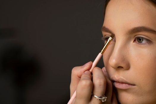 Makeup artist doing a eyebrows makeup on a beautiful woman face. Hand of make-up master is painting eyebrow of young beauty model girl. Make up in process