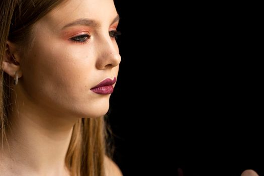 Makeup artist applies red lipstick on a beautiful woman face. Hand of make-up master, painting lips of young beauty model girl. Make up in process