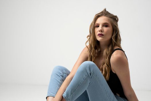 Beautiful young woman portrait in a black t-shirt and blue jeans. Studio shot, isolated on gray background