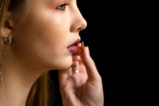 Makeup artist applies red lipstick on a beautiful woman face. Hand of make-up master, painting lips of young beauty model girl. Make up in process