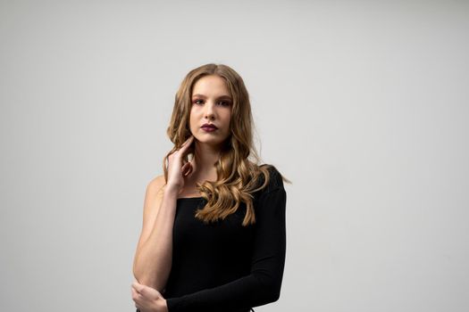 Beautiful young woman portrait in a black t-shirt. Studio shot, isolated on gray background