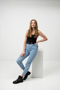 Beautiful young woman portrait in a black t-shirt and blue jeans. Studio shot, isolated on gray background
