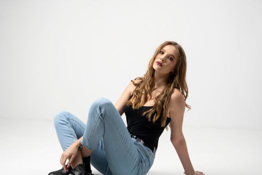 Beautiful young woman portrait in a black t-shirt and blue jeans. Studio shot, isolated on gray background