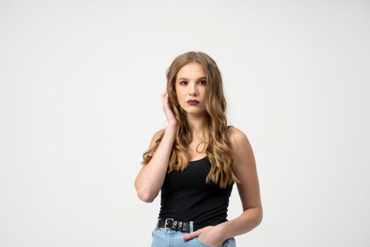 Beautiful young woman portrait in a black t-shirt and blue jeans. Studio shot, isolated on gray background