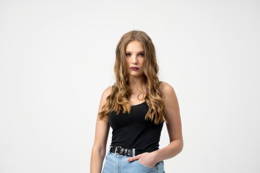 Beautiful young woman portrait in a black t-shirt and blue jeans. Studio shot, isolated on gray background