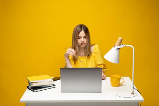 Studio portrait of young successful secretary employee business woman wear yellow t-t-shirt sit work at white office desk with laptop browsing internet online