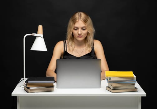 Portrait of a pretty young woman studying while sitting at the table with grey laptop computer, notebook. Smiling business woman working with a laptop isolated on a grey background