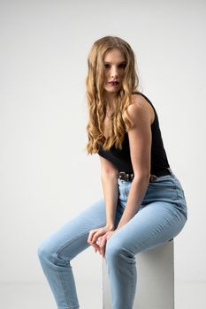 Beautiful young woman portrait in a black t-shirt and blue jeans. Studio shot, isolated on gray background