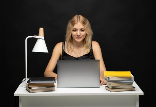 Portrait of a pretty young woman studying while sitting at the table with grey laptop computer, notebook. Smiling business woman working with a laptop isolated on a grey background