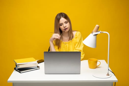 Studio portrait of young successful secretary employee business woman wear yellow t-t-shirt sit work at white office desk with laptop browsing internet online