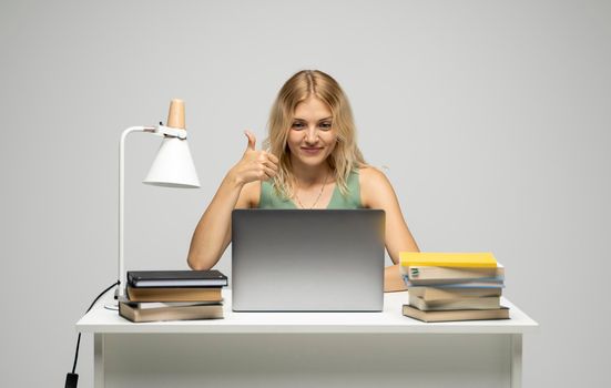 Photo of cute success woman in a green t-shirt show thumb-up to the client or business partner while speaking via web call