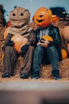 A guy with a pumpkin head sits next to a scarecrow. Halloween Concept