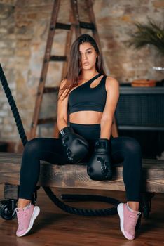 Beautiful confident young fitness girl posing at camera in black boxing glove