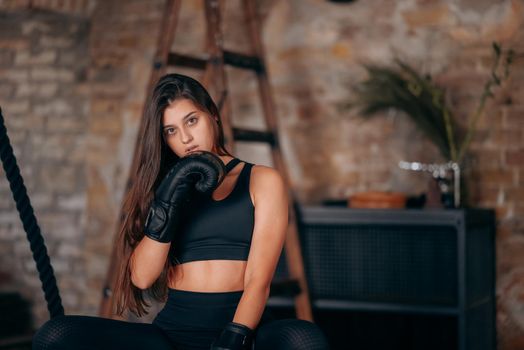 Beautiful confident young fitness girl posing at camera in black boxing glove