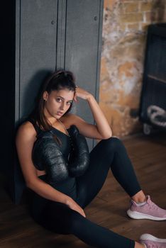 Sporty woman in sportswear posing on camera with boxing gloves. Sport and gym concept