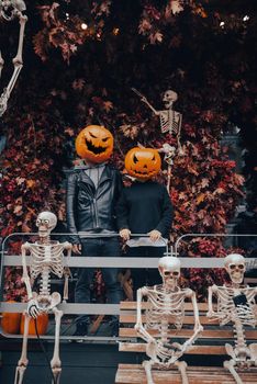 A guy and a girl with a pumpkin heads posing on the street . Halloween Concept