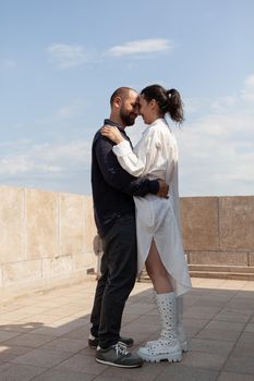 Happy romantic people hugging while standing on tower rooftop celebrating relationship anniversary during summer vacation. Panoramic skyline from tower observation point. Landscape of metropolitan city