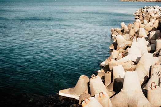 The seashore is reinforced with concrete tetrapods. Protection of the shore from blurring. Sea waves. Concrete tetrapod breakwaters lie all along the coast.