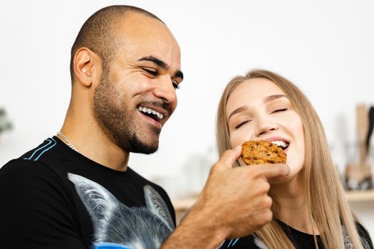 African american guy feeding his girlfriend with a cookie close up