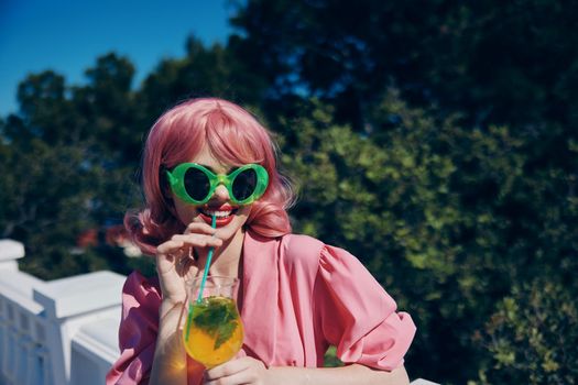 Delighted young girl in green sunglasses with cocktail in summer outdoors Drinking alcohol. High quality photo